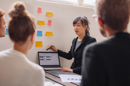Young female executive giving presentation to coworkers
