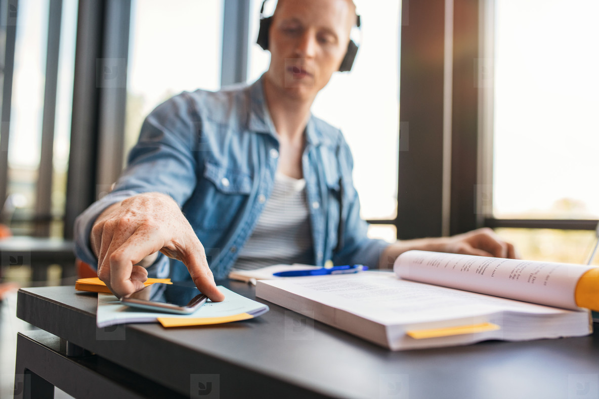Student at college library with books and mobile phone