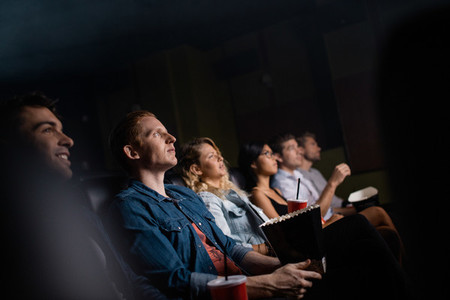 Young man with friends in cinema hall watching movie