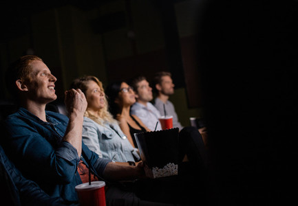 Young man watching movie with friends in cinema