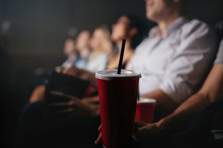 People with soft drinks in movie theater