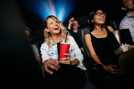Laughing young people watching film in theater