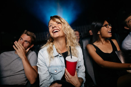 Smiling young woman watching woman in theater