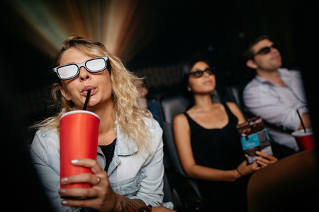 Young woman having cold drink and watching 3d movie