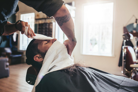 Hairdresser covering face of client with towel