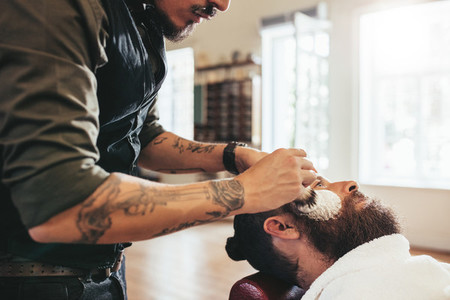 Barber shaving customer in salon