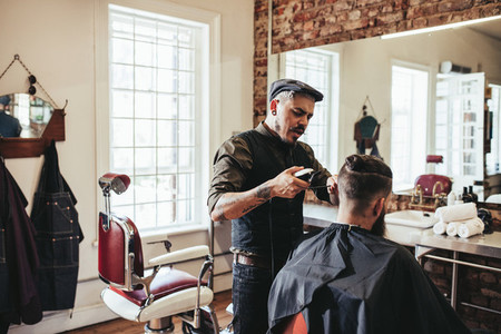 Young man getting trendy haircut at barbershop