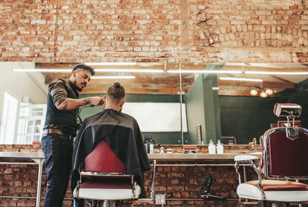 Stylish barber giving haircut to client