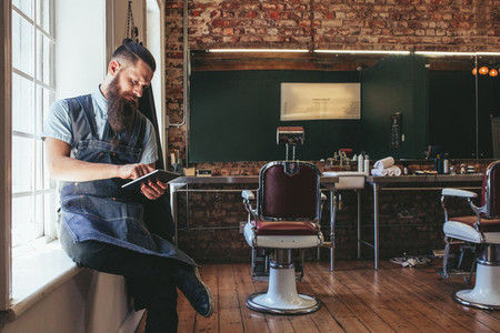 Barber organizing his business using digital tablet