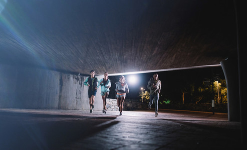 Young men and women jogging together at night