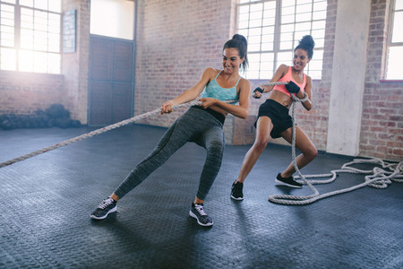 Young women doing rope pulling exercises at a gym