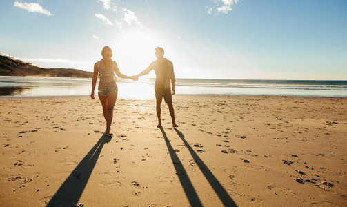 Couple walking on the beach together at sunset