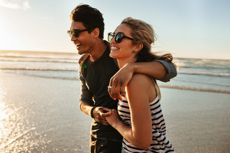 Smiling young couple walking on beach