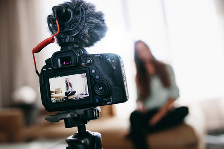 Young woman recording video for her vlog using camera with micro