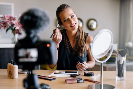 Young female vlogger recording a make up broadcast