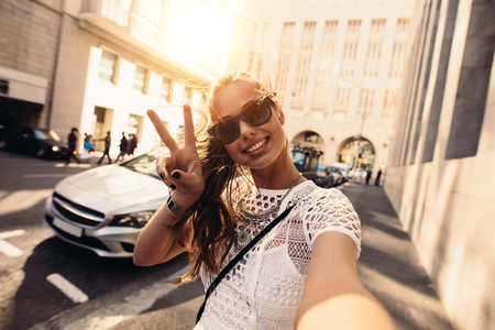 Young woman taking selfie in a street surrounded by buildings
