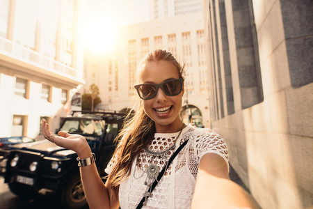 Tourist taking selfie in a street surrounded by buildings
