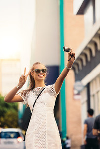 Tourist taking selfie in a street using a digital camera