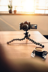 Desk of a photographer with coffee and tripod mounted digital ca