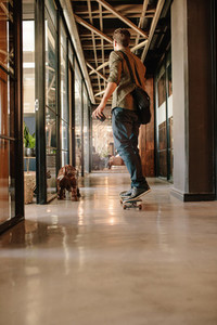 Young man skateboarding in modern office