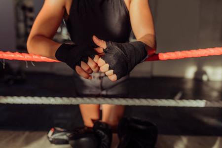 Hands wrapped in black near boxing ring rope