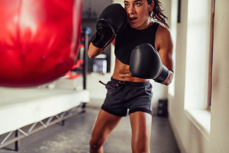 Action shot of woman training on red punching bag