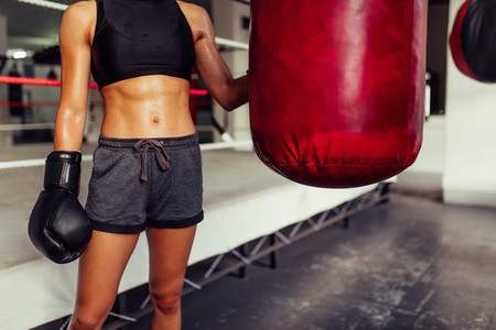 Young female boxer posing with a punching bag