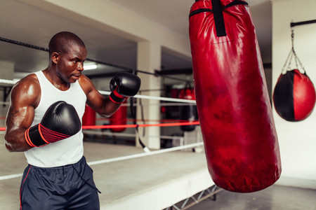 Focused muscular African boxer in a gym