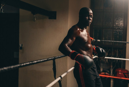 Muscular young African boxer resting in his corner