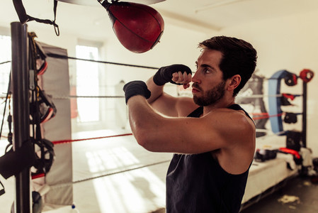 Handsome boxer with beard strikes punching bag