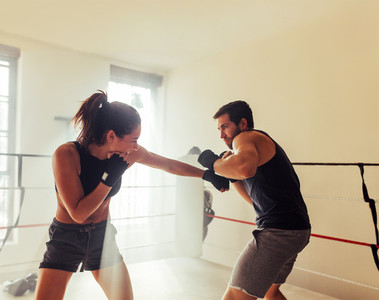 Male and female athletes sparring in boxing ring