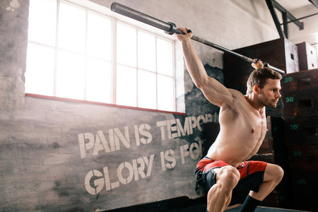 Young man at crossfit gym lifting barbell