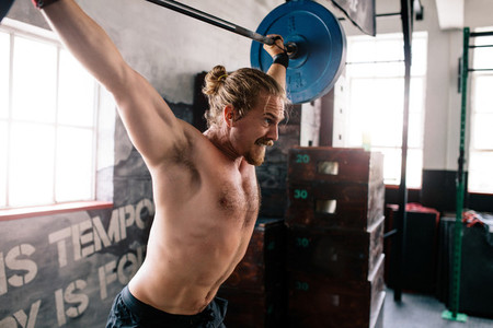 Muscular man lifting weights at a gym