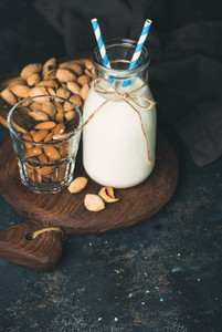 Fresh almond milk in glass bottle served with almonds