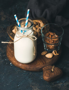 Fresh almond milk in glass bottle served with almonds