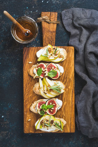 Crostini with fruits  cheese and herbs on rustic wooden board