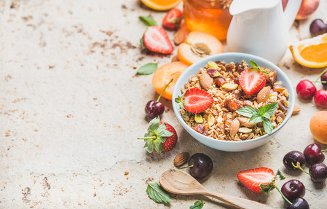 Healthy breakfast ingredients Bowl of oat granola with milk fresh fruit berries and honey