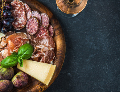 Italian antipasti snack for wine on wooden tray  dark background