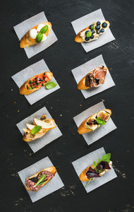 Italian crostini with various toppings on white baking paper