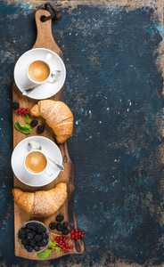 Freshly baked croissants with garden berries and coffee cups