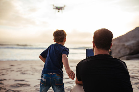 Father and son on the beach flying drone