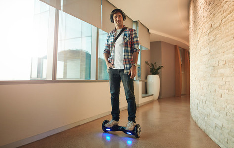 Young man on an electrical self balancing scooter in office