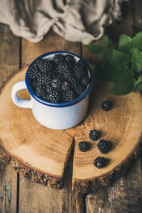 Fresh garden Blackberries in white cup on round serving wooden