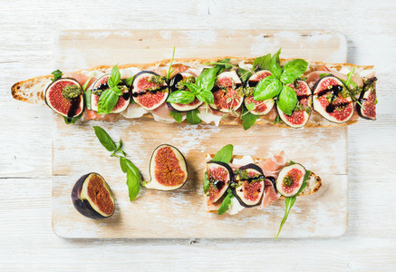 Long baguette sandwich with prosciutto mozzarella arugula figs and basil