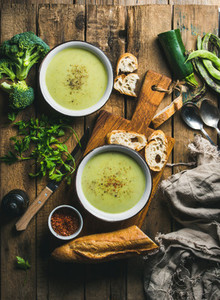 Two bowls of homemade pea broccoli and zucchini cream soup
