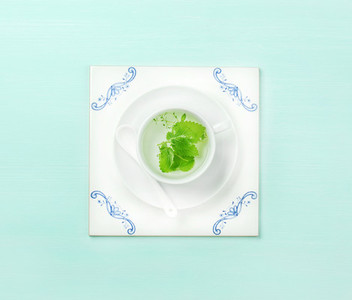 Cup of tea on white tile board over mint background
