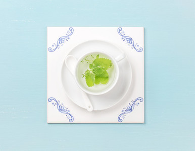 Cup of tea on white tile board over sky blue background