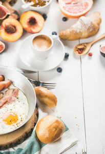 Fried egg with sausages and bacon  bread  croissants  coffee