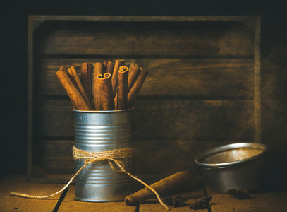 Cinnamon sticks in tin can  rustic wooden background  copy space