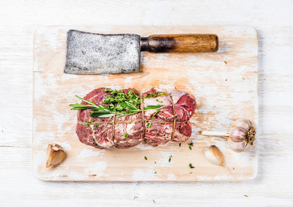 Raw roastbeef meat cut with herbs over white wooden background